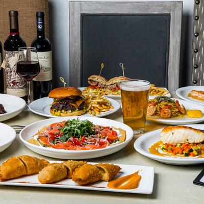 Assorted dishes on a table, accompanied with glasses of wine and a beer.