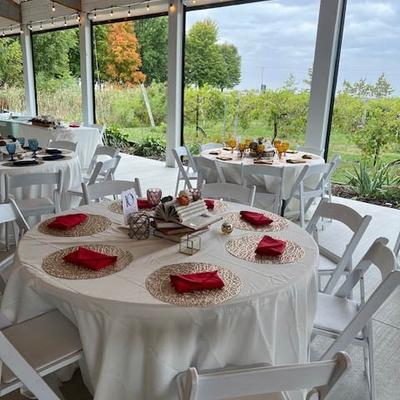 Indoor wedding reception venue, round tables with place settings, overlooking a vineyard.