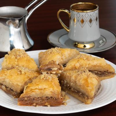 Baklava Triangles on a plate, accompanied with a Turkish coffee pot and a cup.