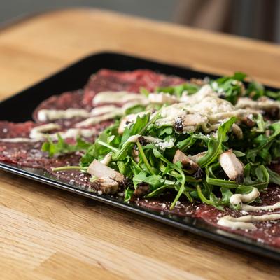 Beef Carapaccio topped with arugula, mushrooms and Parmesan cheese.