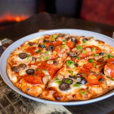 Pepperoni and sausage pizza, with olives and scallions.