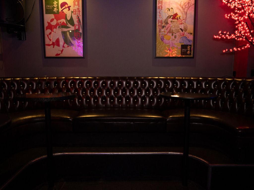 Leather seating with tables by a wall with retro posters and red light tree

            