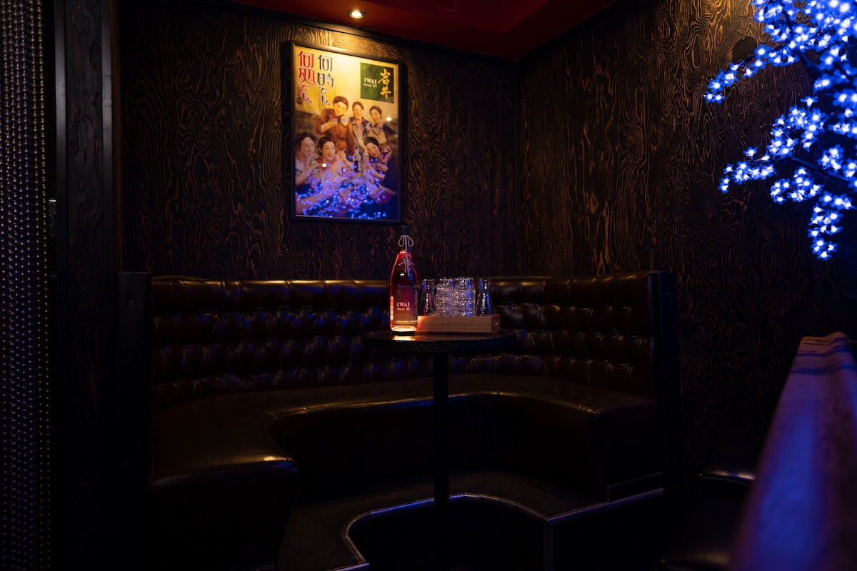 Private booth seating with vintage poster on the wall and blue light coming from a decorative tree