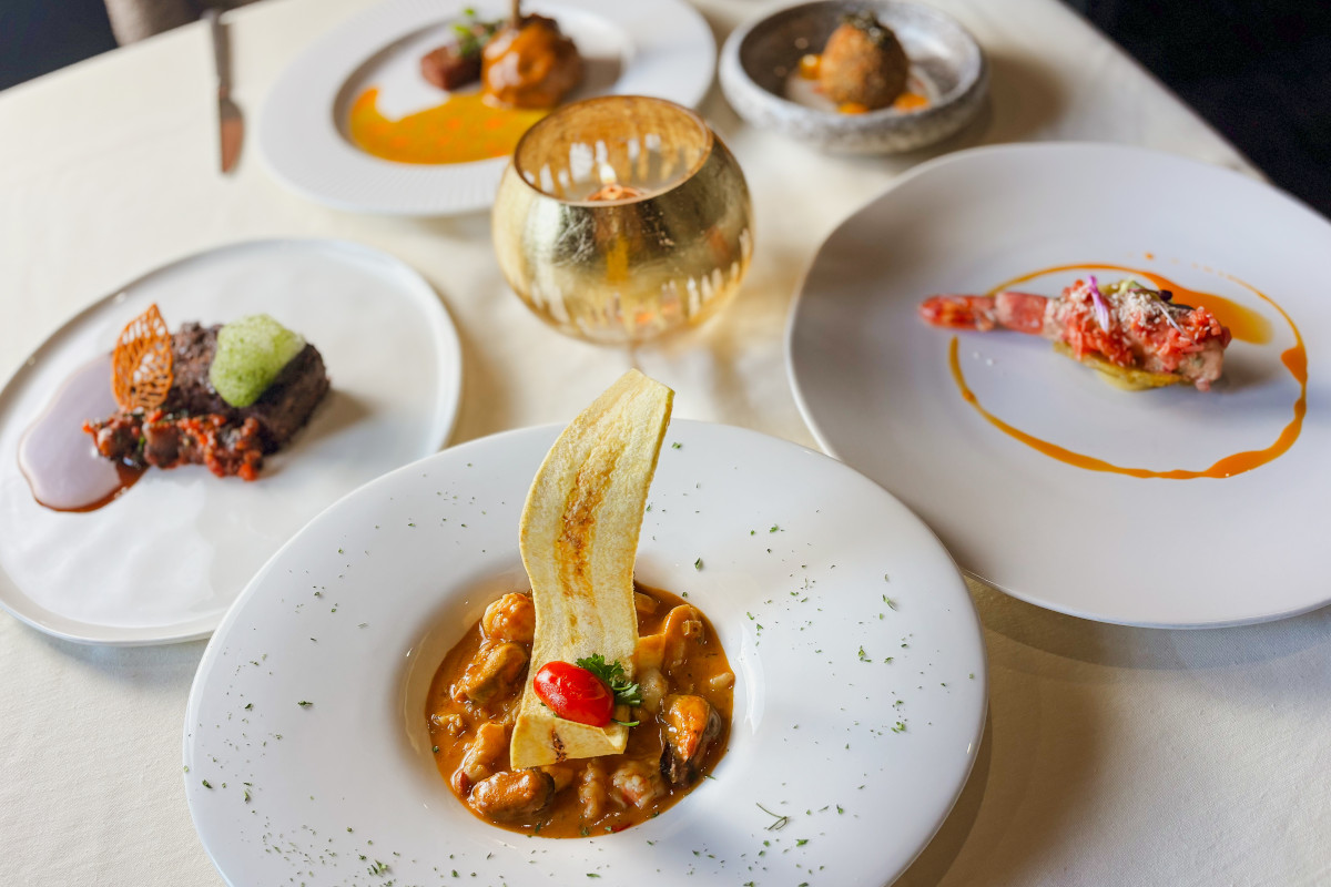 A table set with four plates of various dishes