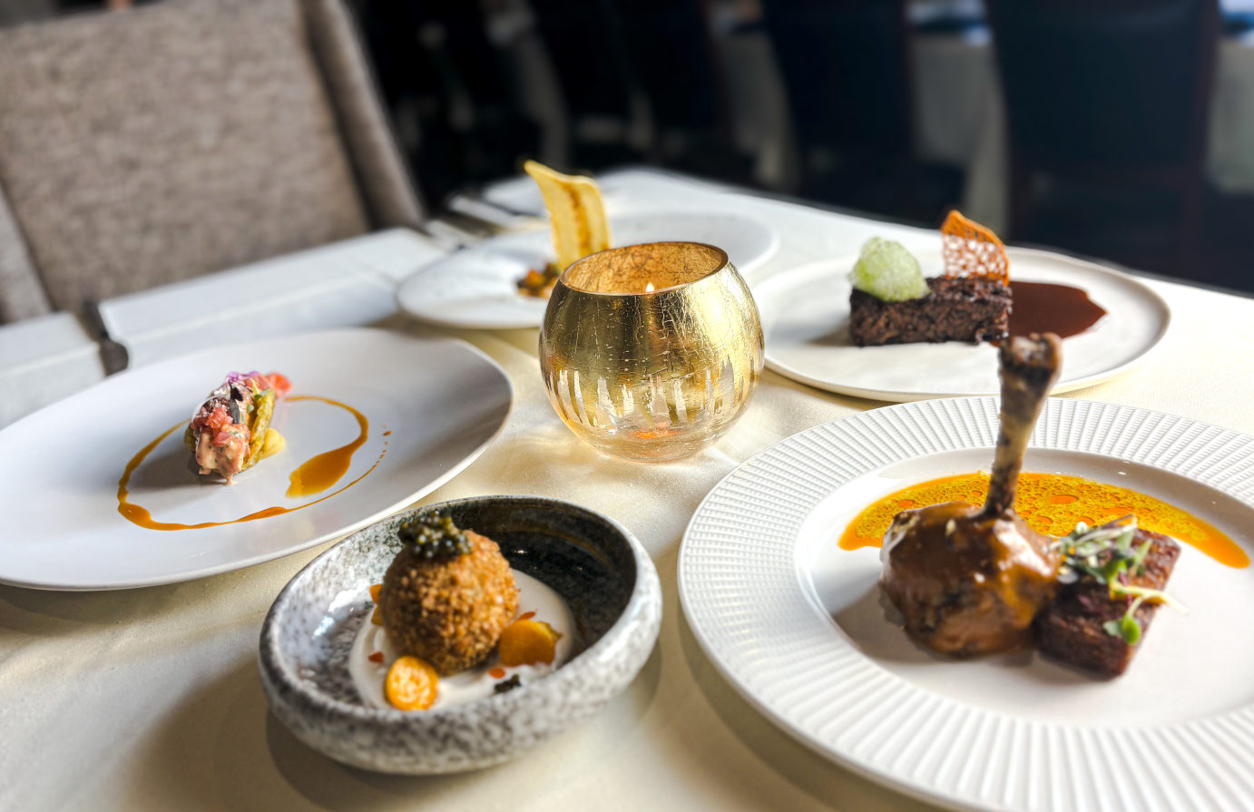 A table set with four plates of various dishes