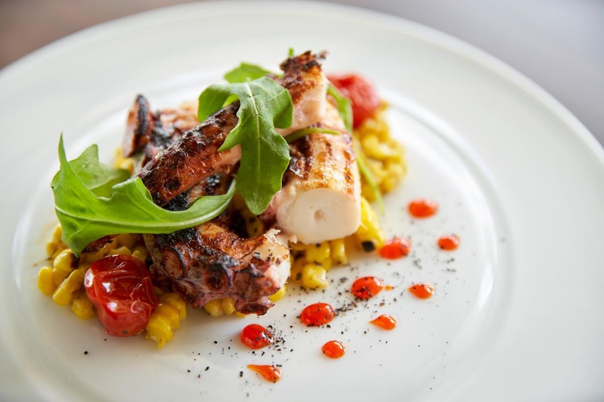 Grilled octopus served atop corn and cherry tomatoes
