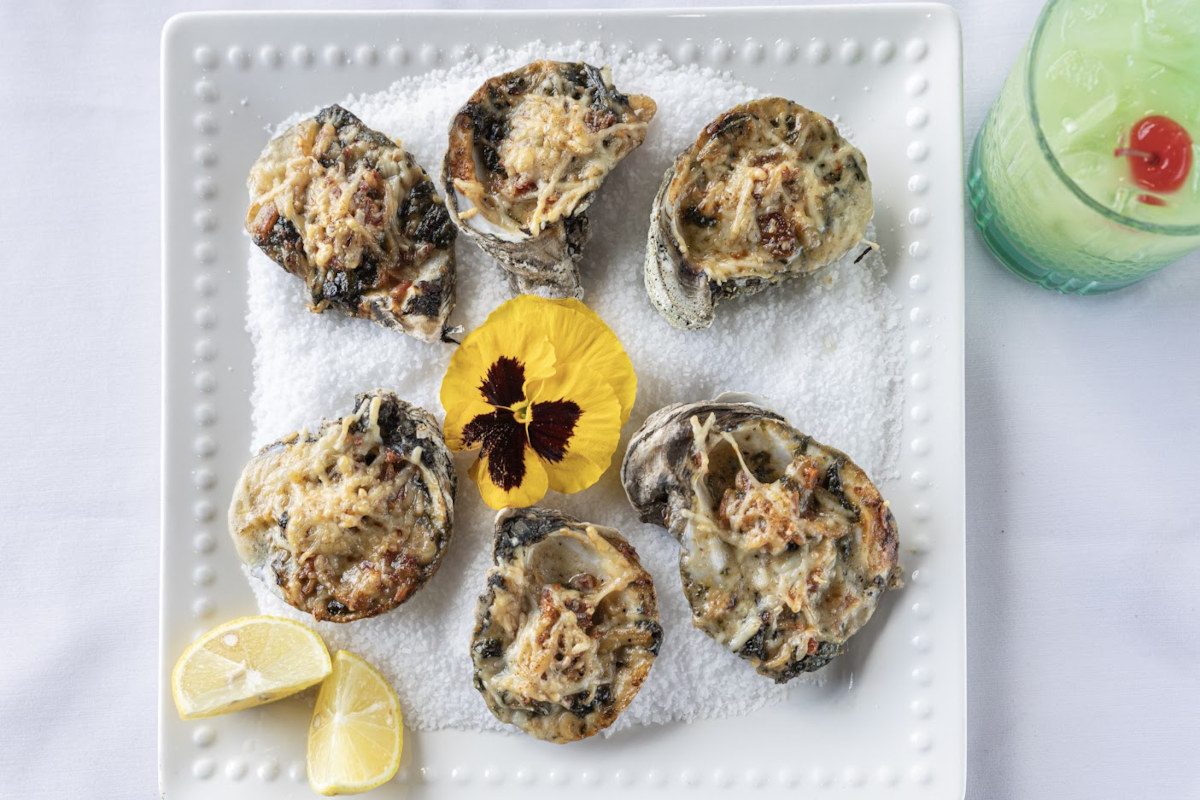 oysters on a white plate with lemon wedges.