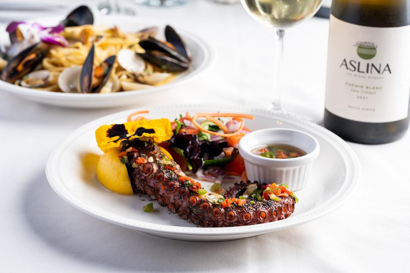 a plate of food and a bottle of wine on a table.