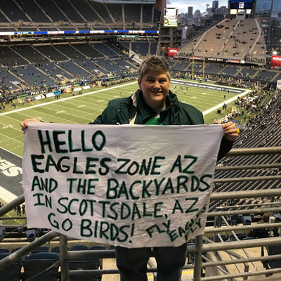 A fan posing with a flag with a message at the stadium
