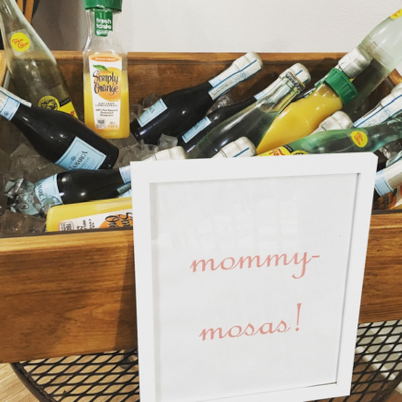 A collection of champagne bottles and orange juice with a sign reading 