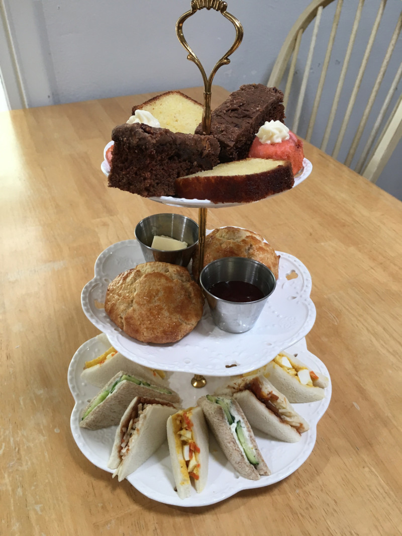 A tiered tray with scones and cake on a table.