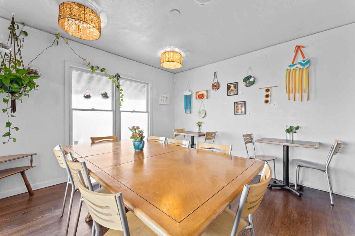 A bright indoor dining room with a large wooden table, chairs, and wall-mounted planters.