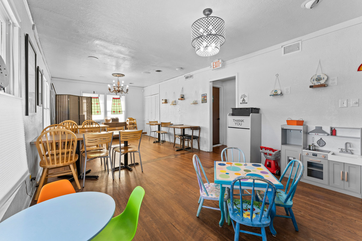 A spacious indoor dining area adorned with children's artwork and multiple wooden tables.