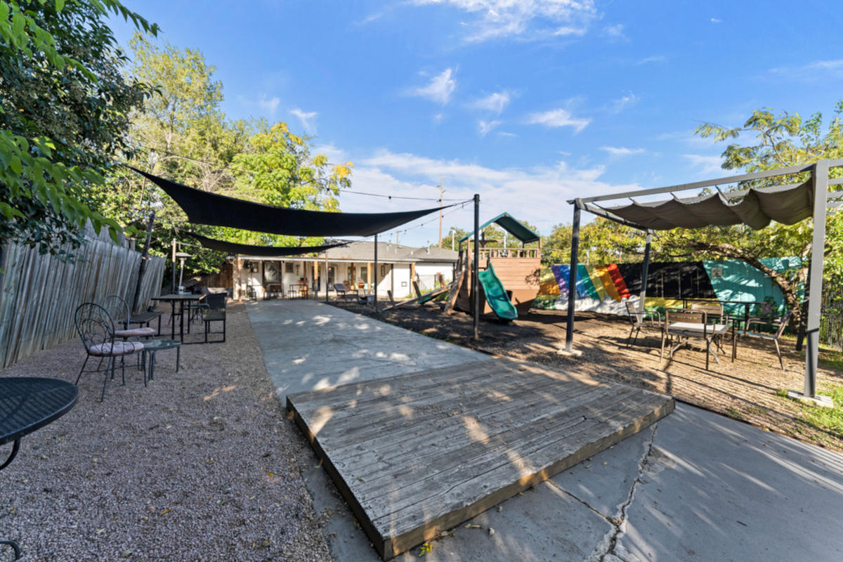 An outdoor recreational space with seating, play structures, and protective canopies.