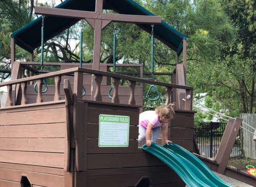 exterior, a child descends down the slide
