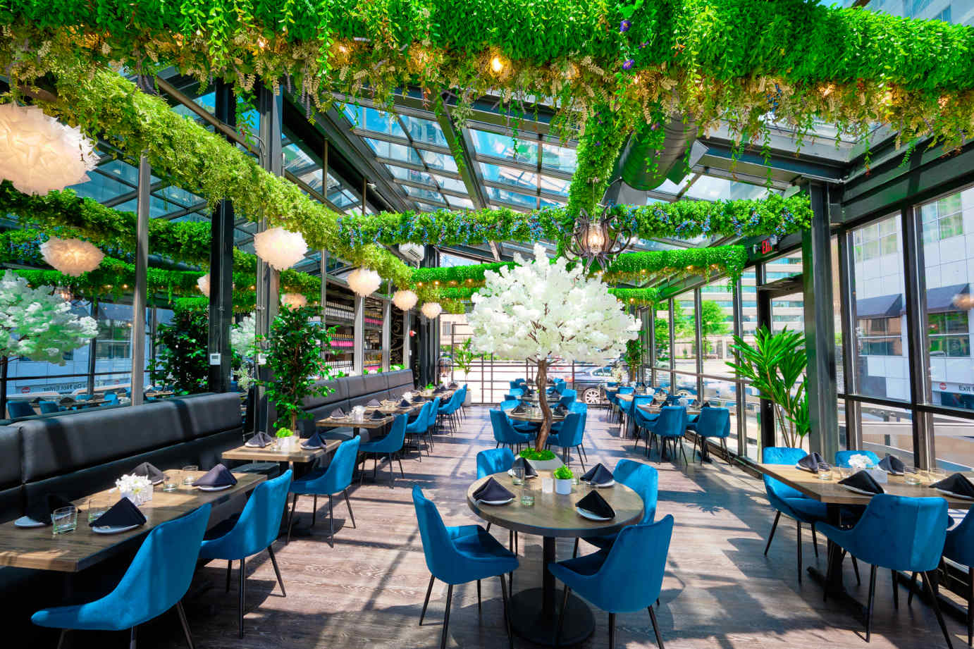 Glass covered patio with greenery decorations, set tables and seating
