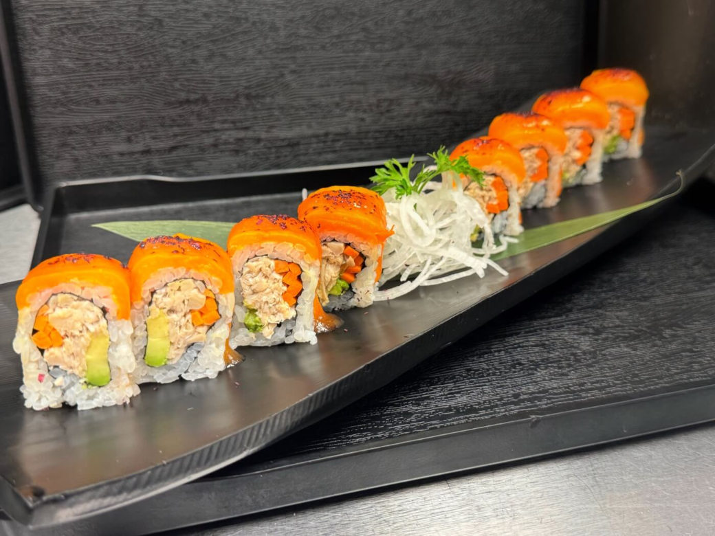 Plate of sushi rolls with orange topping.