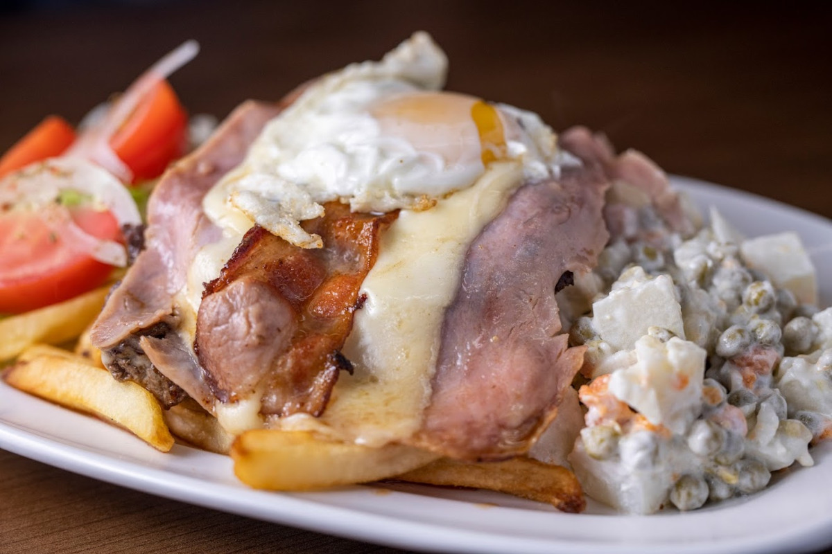 Beefsteak slice topped with ham, bacon, fried egg and mozzarella