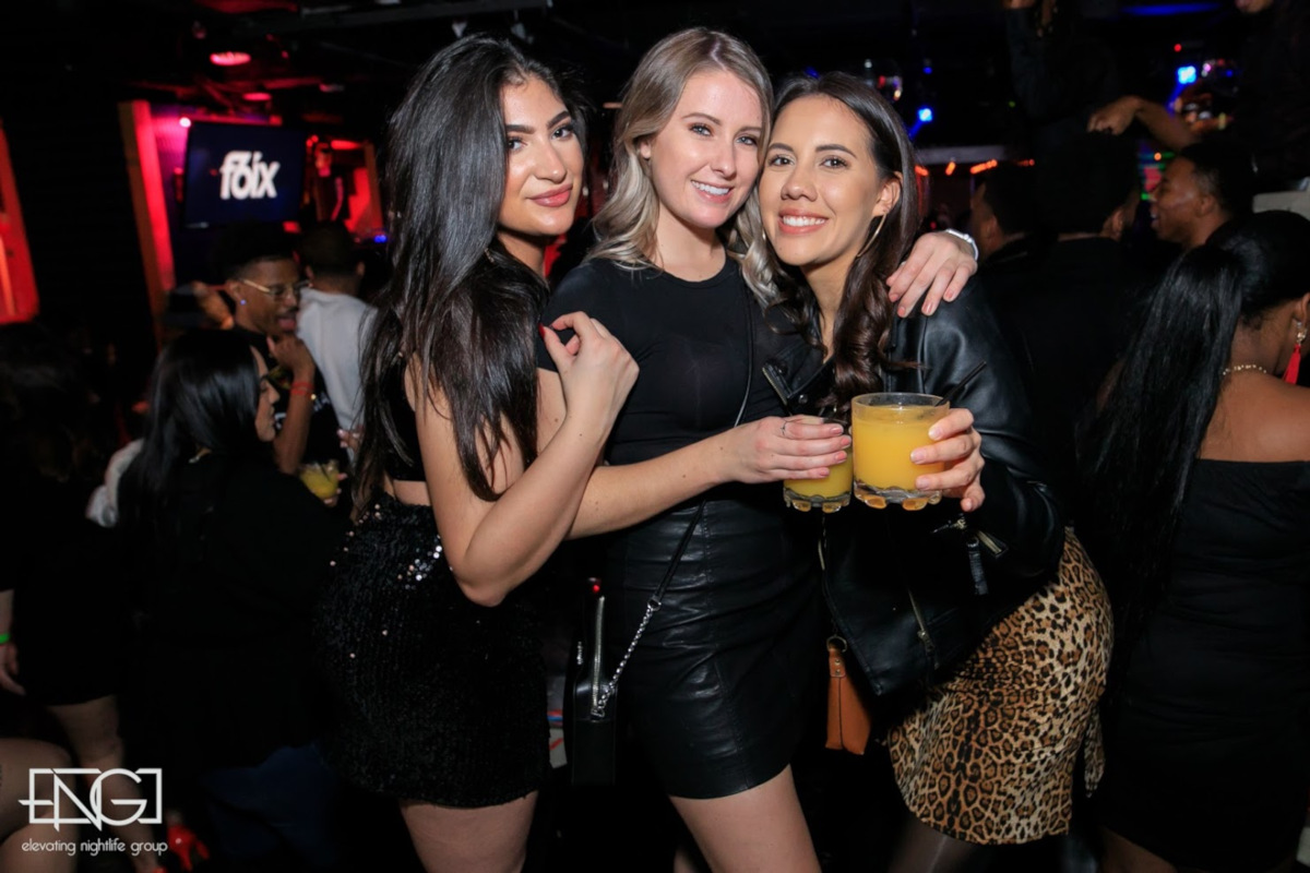 Three girls having fun in the club, posing for a photo
