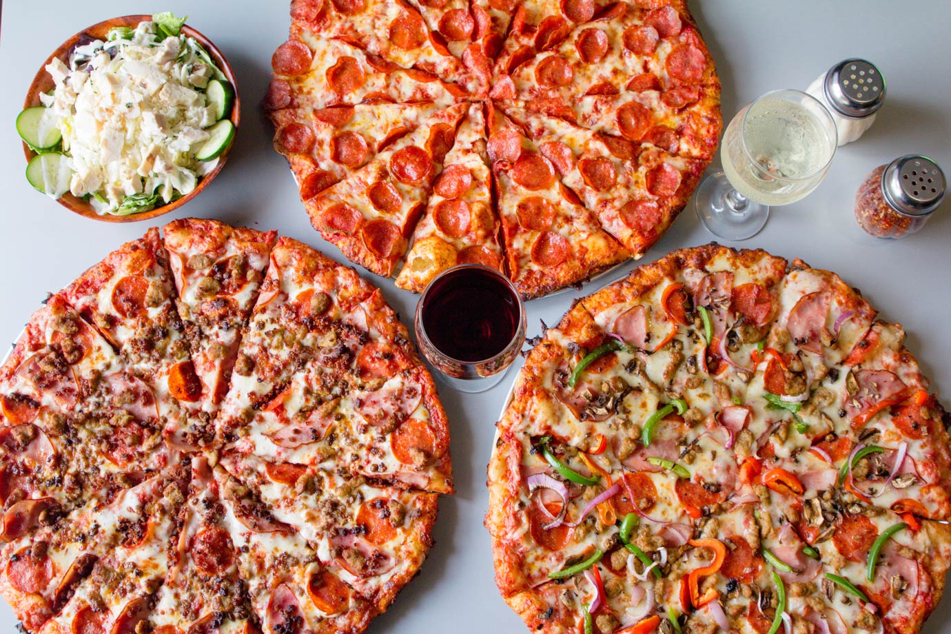 three pizzas, two glasses of wine and a salad