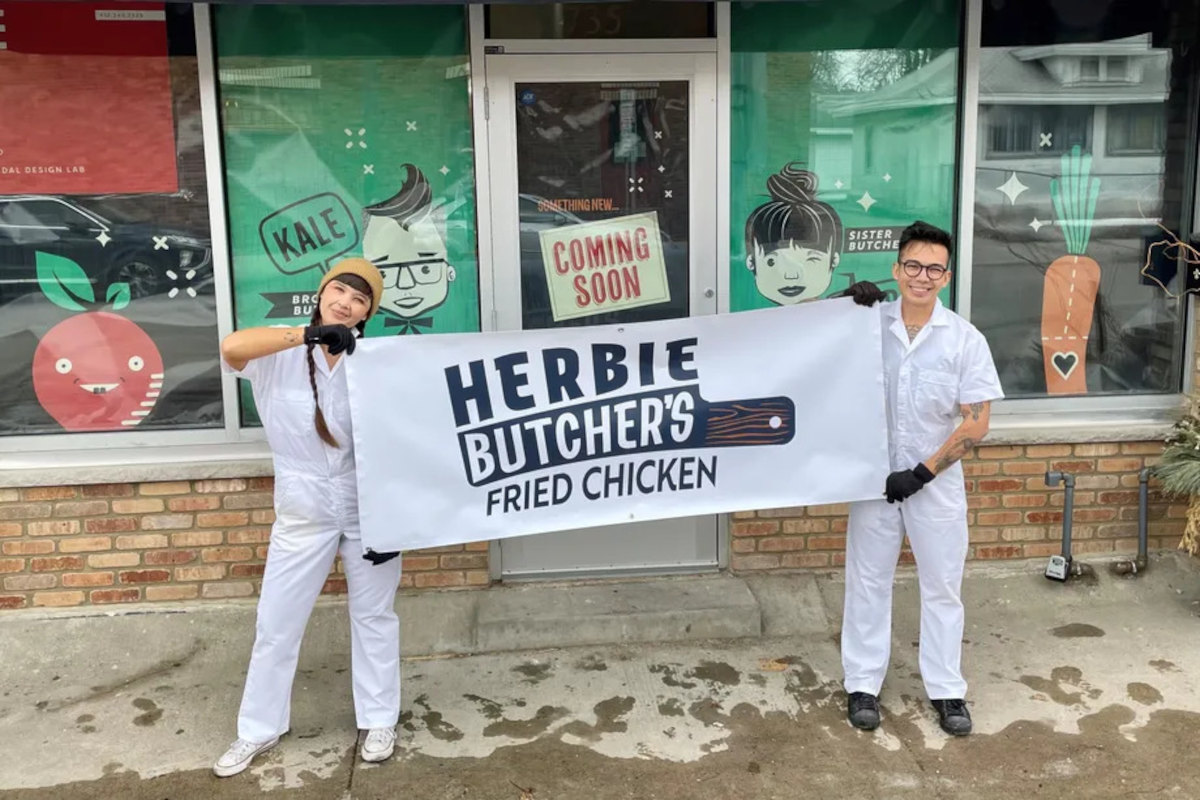 Aubry and Kale hold a banner, “Herbie’s Fried Chicken” in front of the new storefront