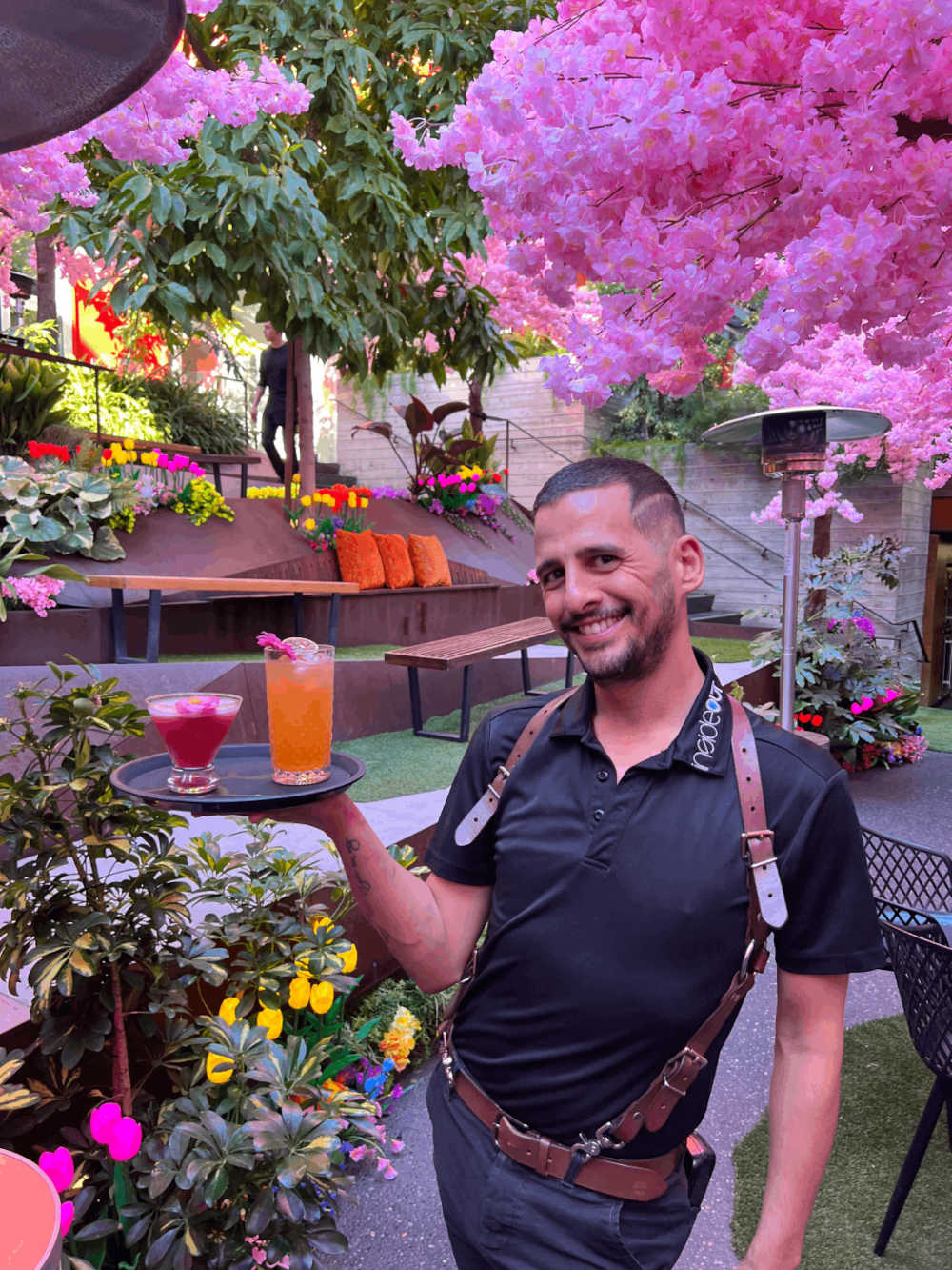 A person standing in a garden holding a tray with drinks