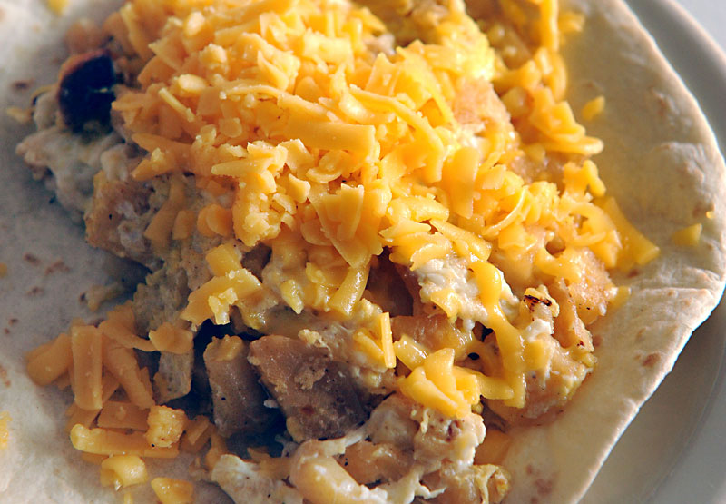 Tortilla topped with pork and shredded cheese