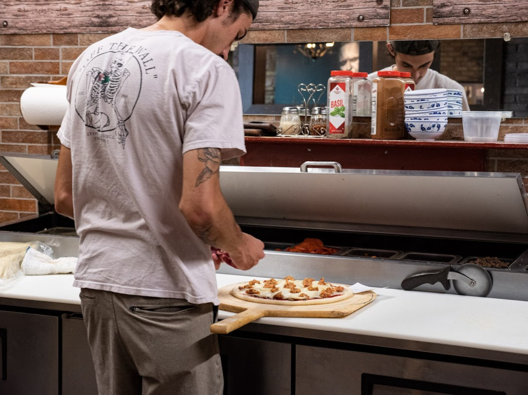 Staff member preparing pizza