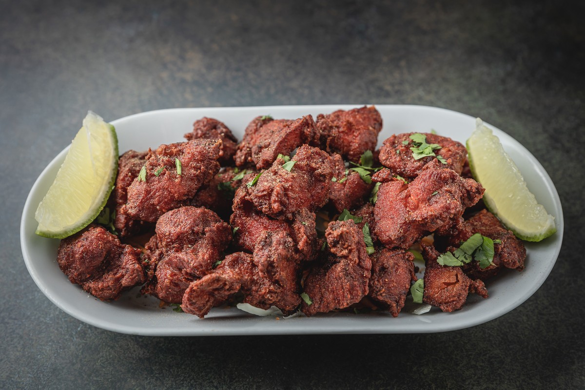 A plate of golden-brown fried chicken accompanied with lime wedges