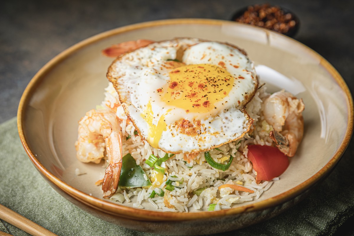 Fried egg served over rice with veggies and shrimp