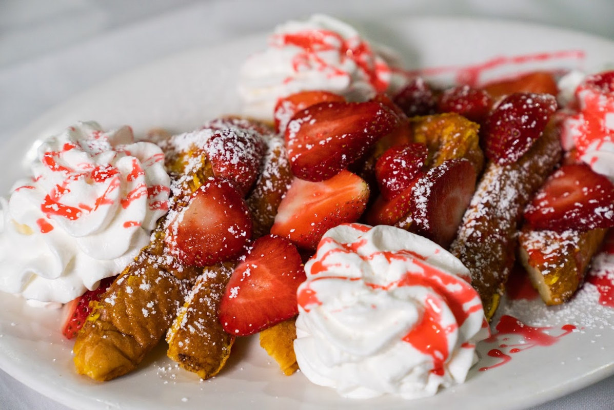 French Toast dipped in batter and served with plenty of strawberries and syrup