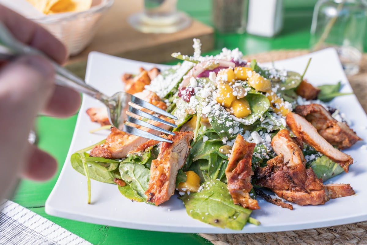 Mango salad with arugula, spinach leaves, grilled chicken and cheese