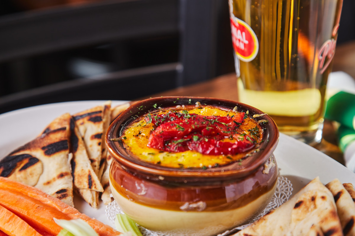 A pot with melted cheese dish, served with grilled pita