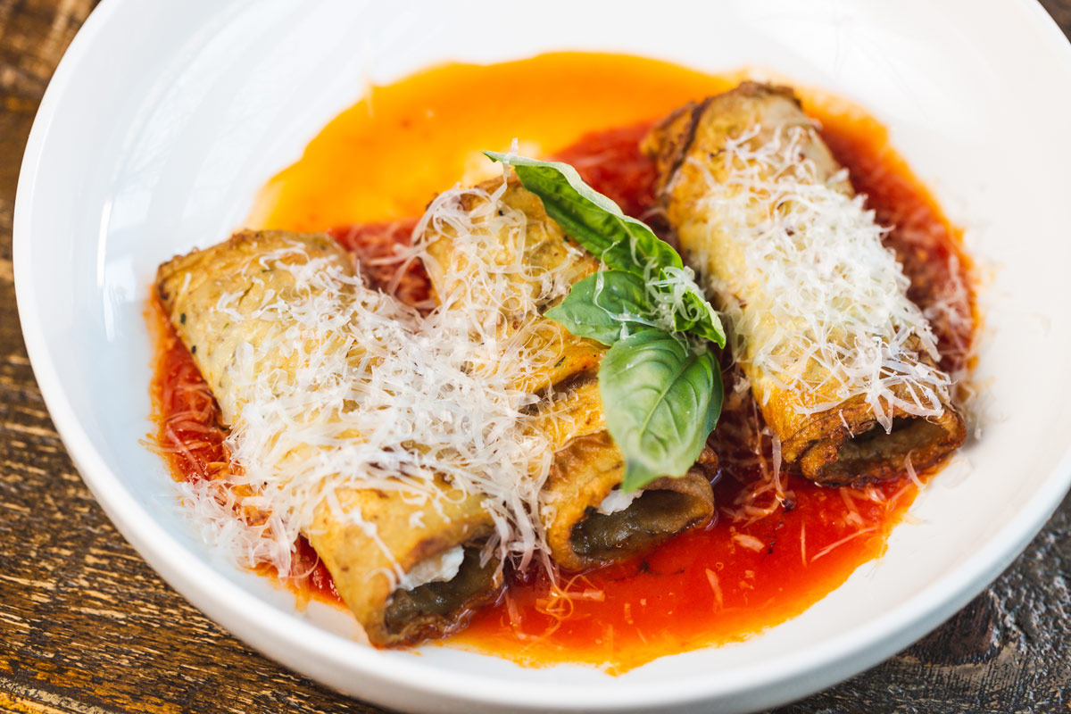 Canneloni in sauce, topped with cheese