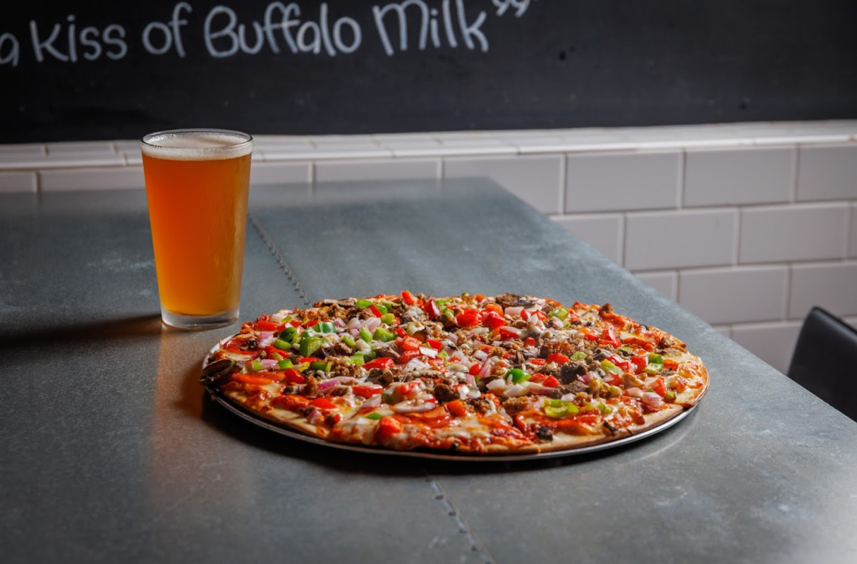 The Mother Lode pizza served on the table with a glass of beer

    