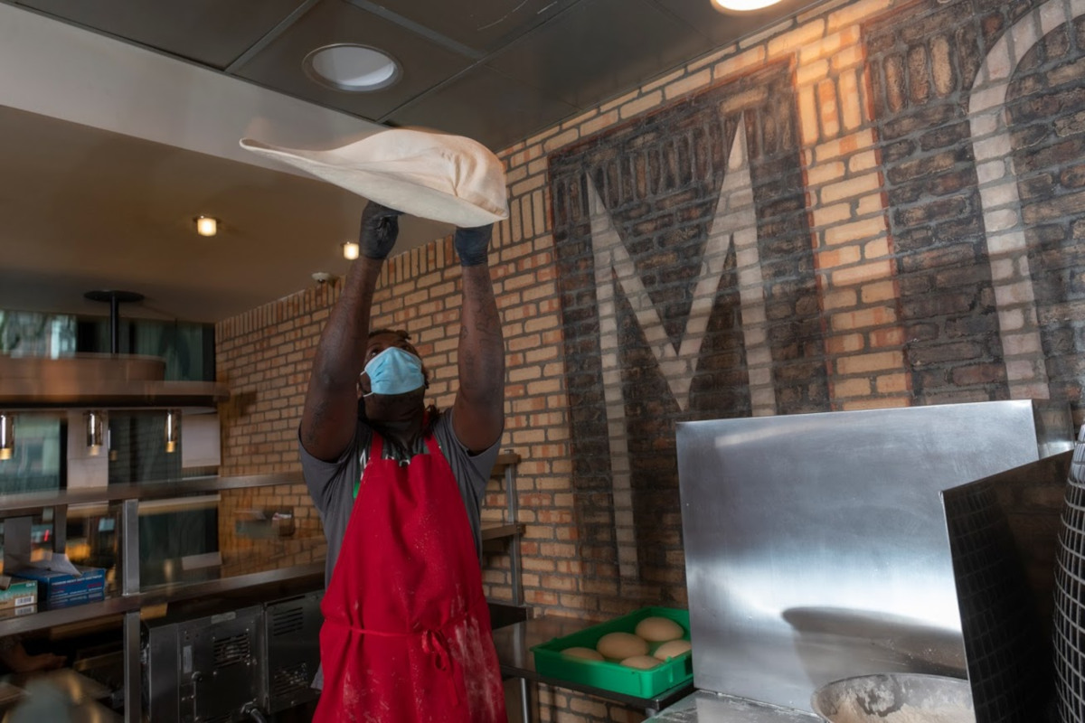 Staff member working in the kitchen, preparing pizza