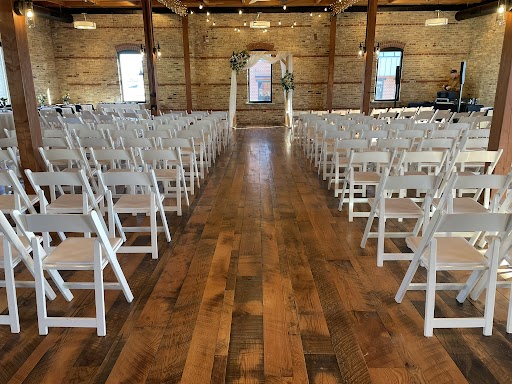 Indoor wedding ceremony setup with white chairs and arch