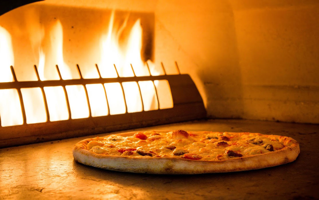 pizza in front of the stone stove