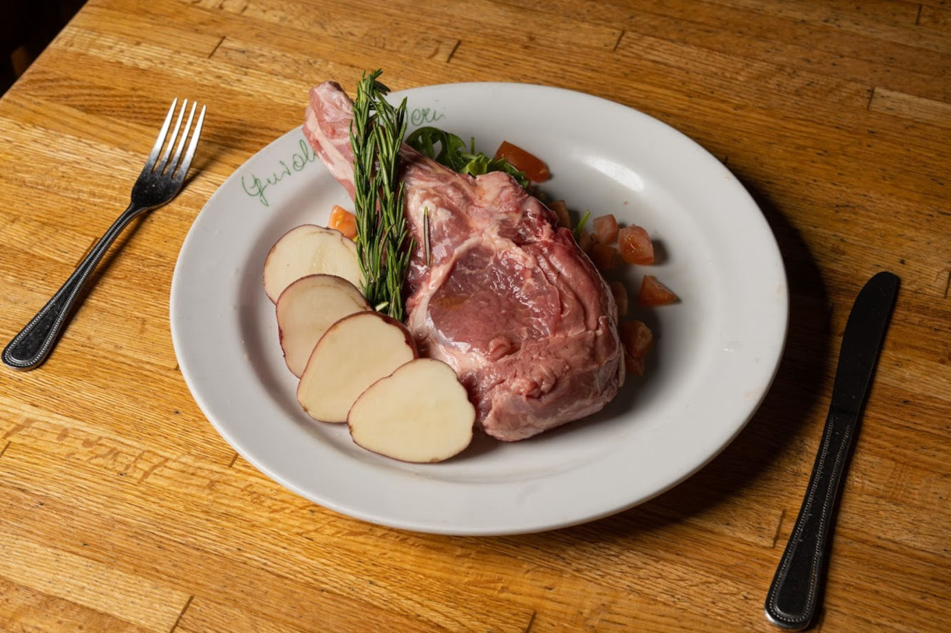 Raw chop with rosemary and potatoes on the plate