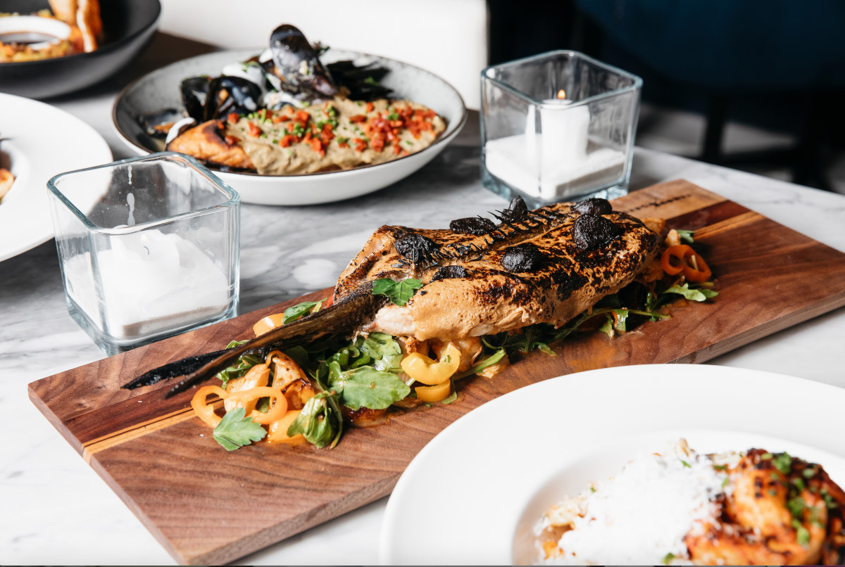 Whole grilled sea bass, served on a board