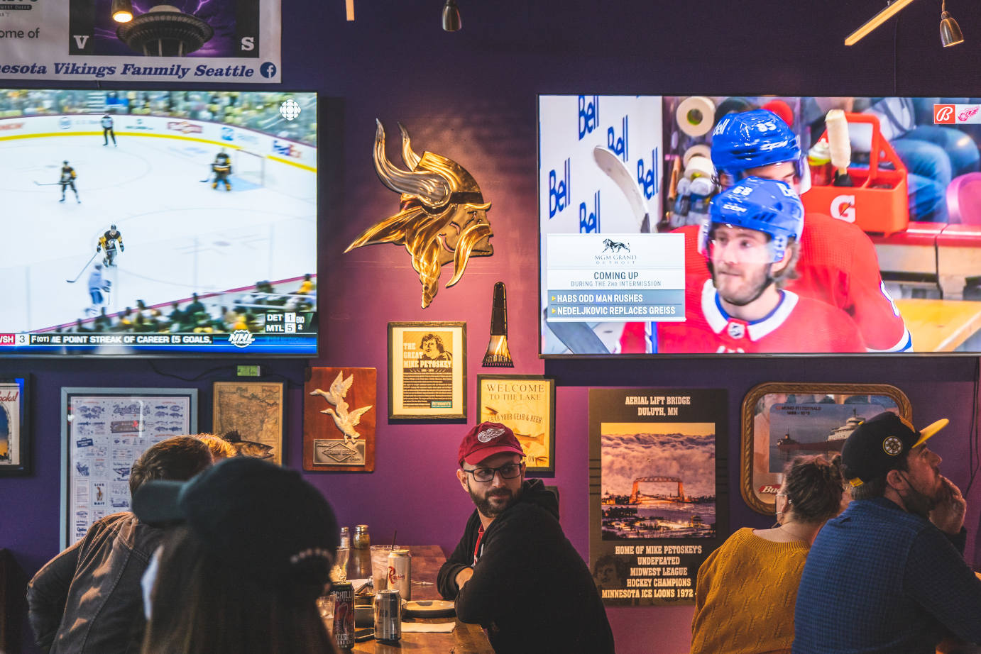 Interior, people watching hockey match broadcasts on large TV screens