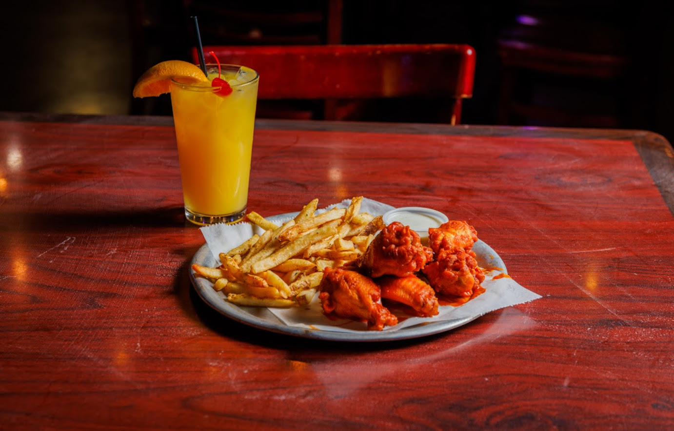 Buffalo wings, fries, sauce dip, and a cocktail.