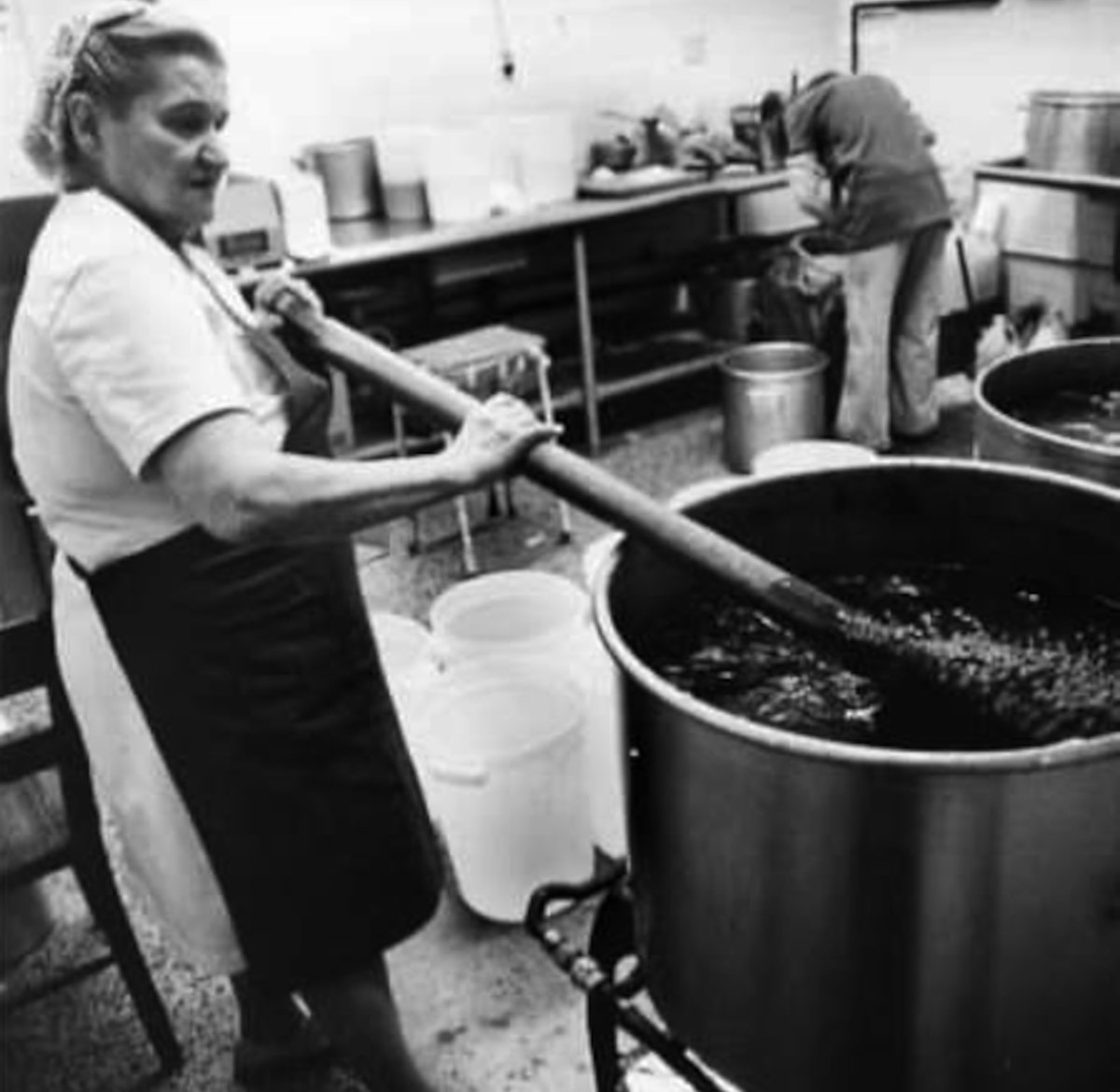 Staff member stirring big pot, black and white photo