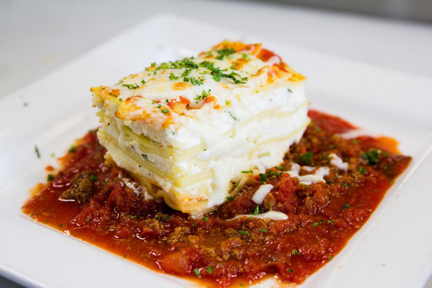 White lasagna with red tomato sauce on the side
