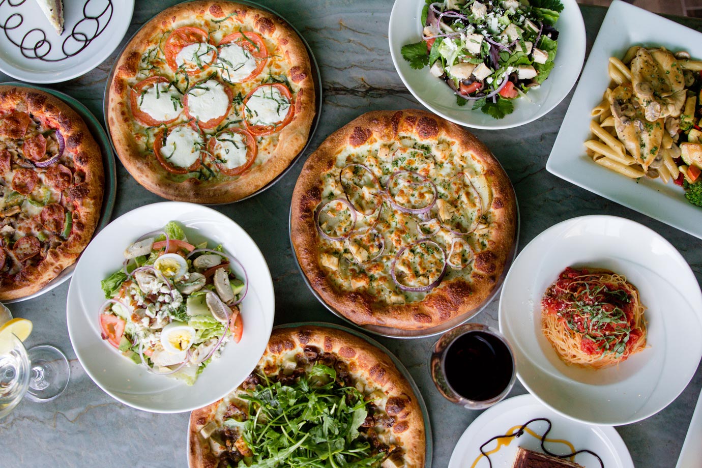 Different types of pizza and salads on the table