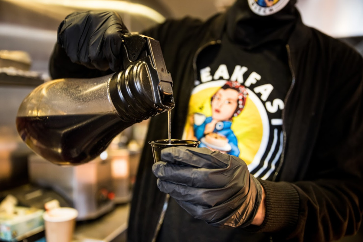 Staff member pouring a coffee in gloves