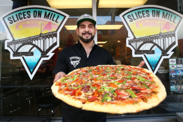 Staff member holding big pizza