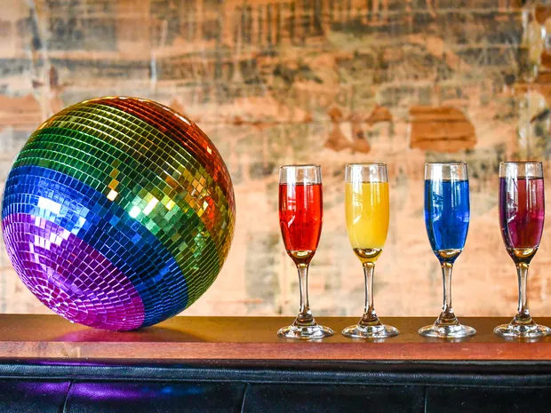 A colorful disco ball on a bar counter next to four champagne flutes