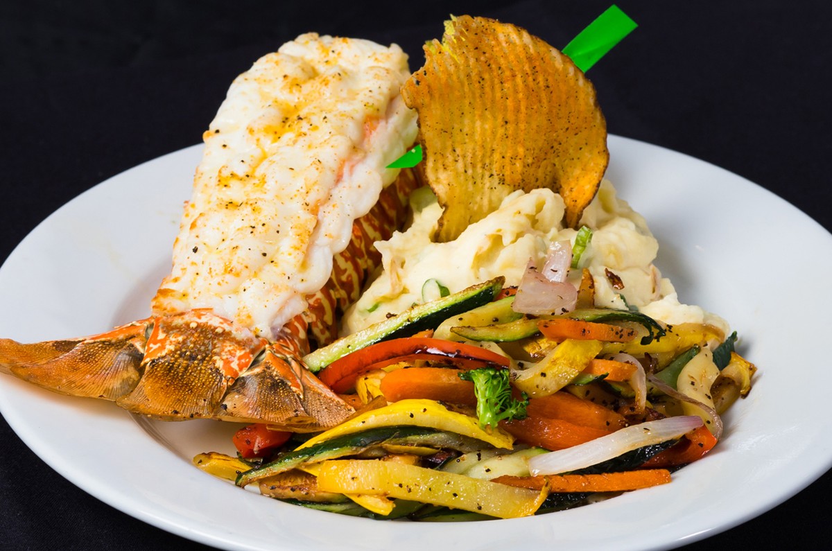 A white plate with a lobster and vegetables on it.