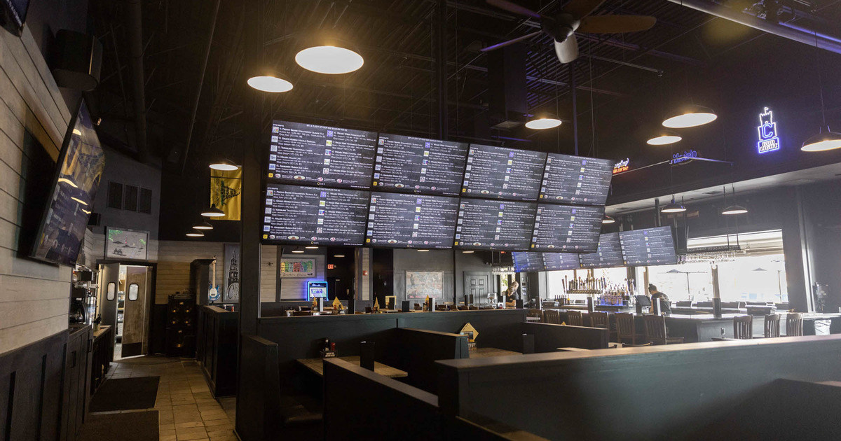 Interior, tables set for customers, screens hanging from the ceiling